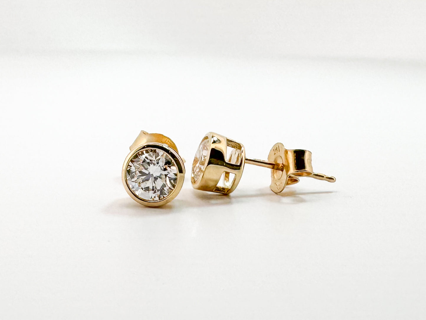14k, 1.00 ctw lab grown bezel set diamond stud earrings.