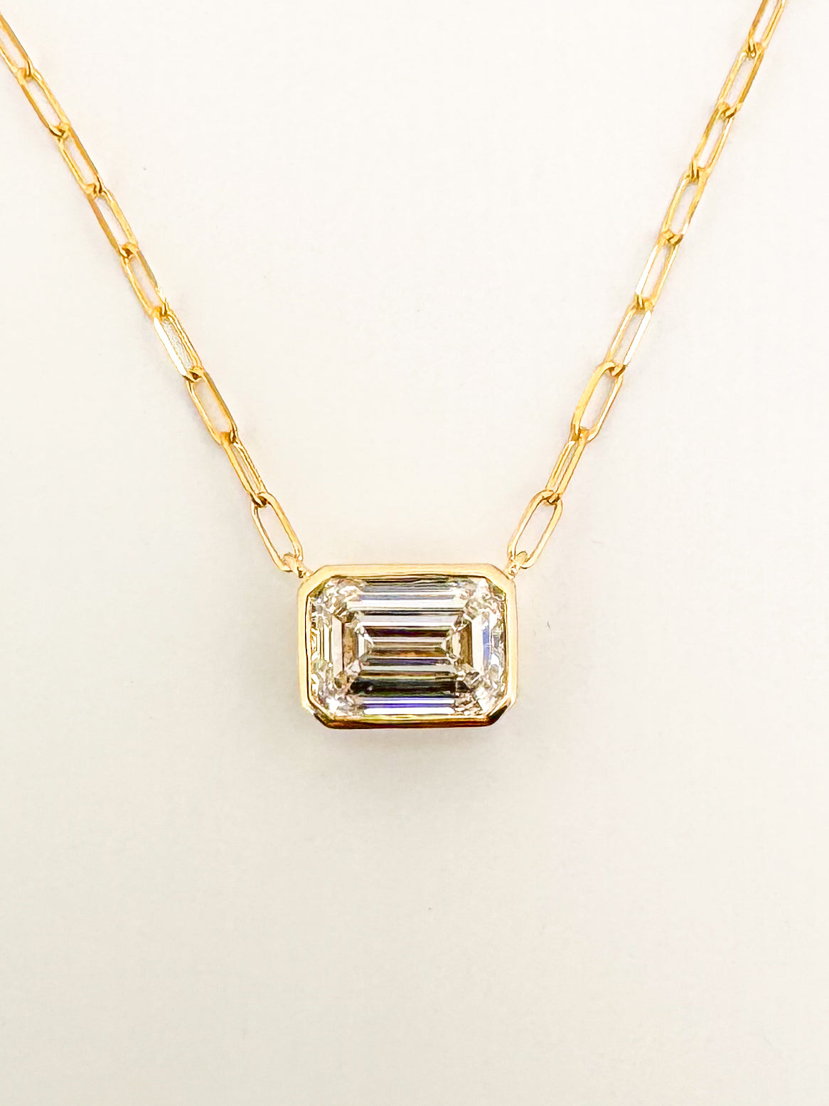 14K yellow gold 2.00 E VVS2 Emerald cut lab diamond bezel set pendant. IGI certified