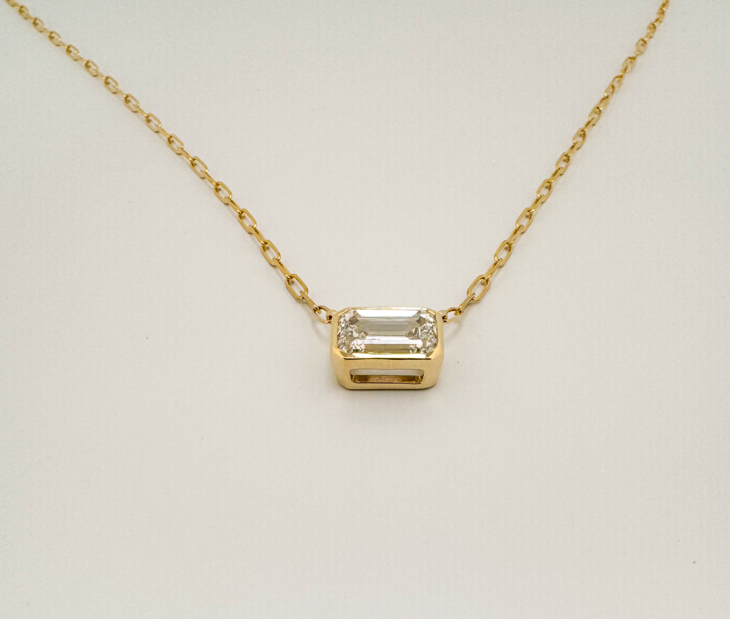 14K yellow gold 2.00 E VVS2 Emerald cut lab diamond bezel set pendant. IGI certified