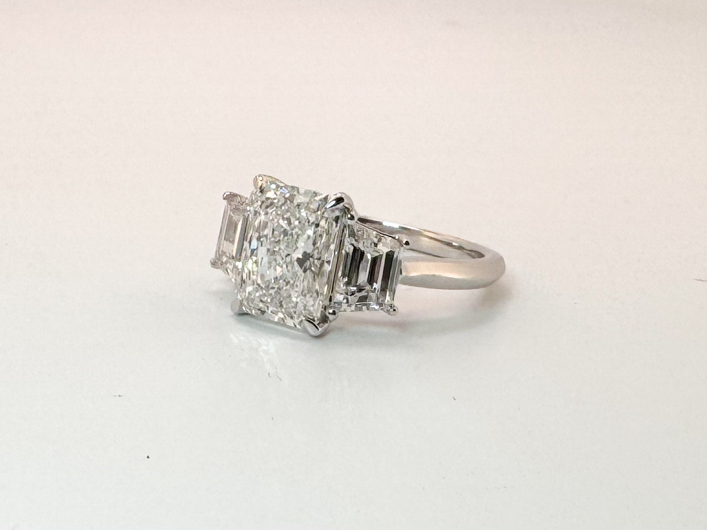 14K white gold 2.58 center radiant cut lab diamond set with 1.29 carat lab grown step shield side diamonds.